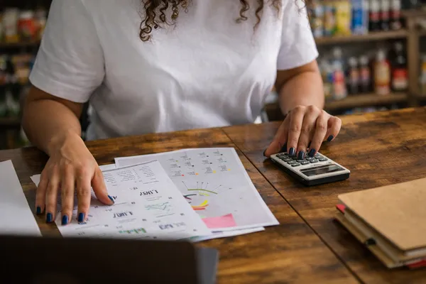 Persona registrando gastos y revisando su presupuesto con calculadora y documentos.